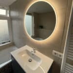 Ronde badkamer spiegel met verlichting op grote horizontale tegels