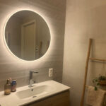 Ronde badkamer spiegel op een crème tegel met relief