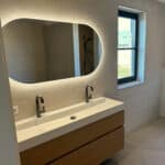 Ovale badkamer spiegel op zand kleurige tegelwand