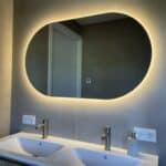 Ovale badkamerspiegel op grote grijze tegel