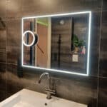 Spiegel met scheerspiegel op grijze tegelwand